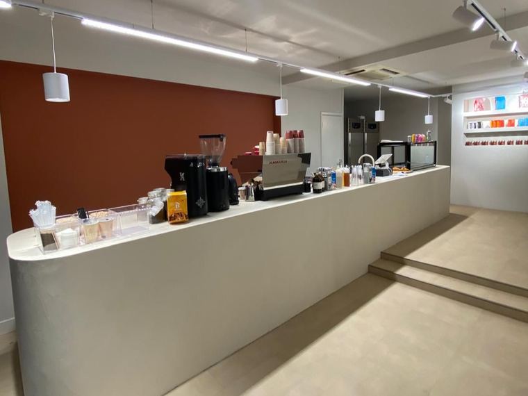 Gestucte bartoog in beton ciré met een terracotta accentwand in een koffiezaak