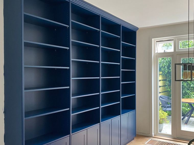 Op maat gespoten diepblauwe kastenwand in een woonkamer met visgraatvloer